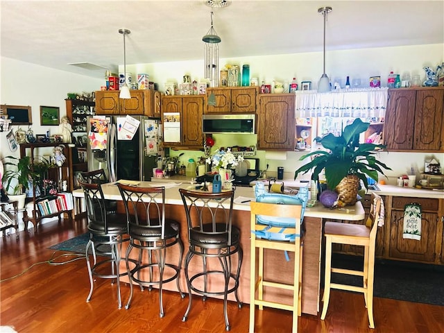 9275 N 890th St, Effingham, IL 62401 - kitchen featuring stainless steel fridge with ice dispenser, light countertops, dark wood-type flooring, pendant lighting, and a kitchen breakfast bar