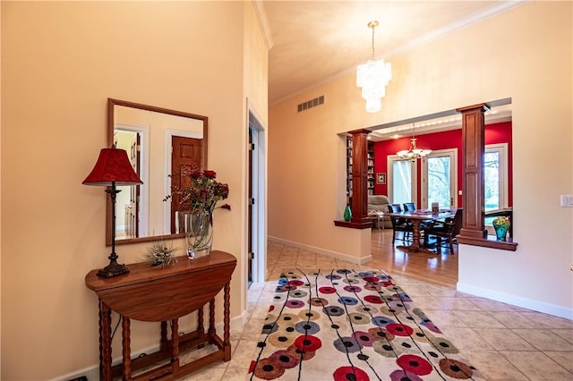 hallway featuring tile patterned flooring, an inviting chandelier, visible vents, ornamental molding, and decorative columns