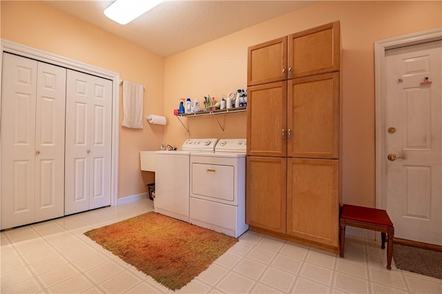clothes washing area with washing machine and dryer, baseboards, and cabinet space