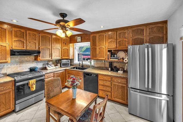 4170 N Taylor Ave, Decatur, IL 62526 - kitchen featuring appliances with stainless steel finishes, under cabinet range hood, light tile patterned flooring, brown cabinetry, and recessed lighting