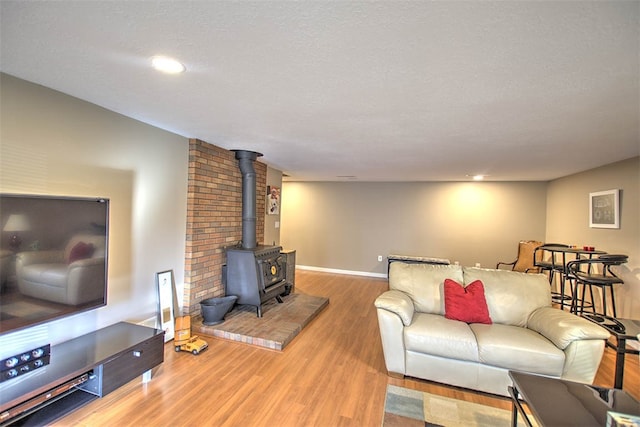 living room with a textured ceiling, hardwood / wood-style flooring, and a wood stove