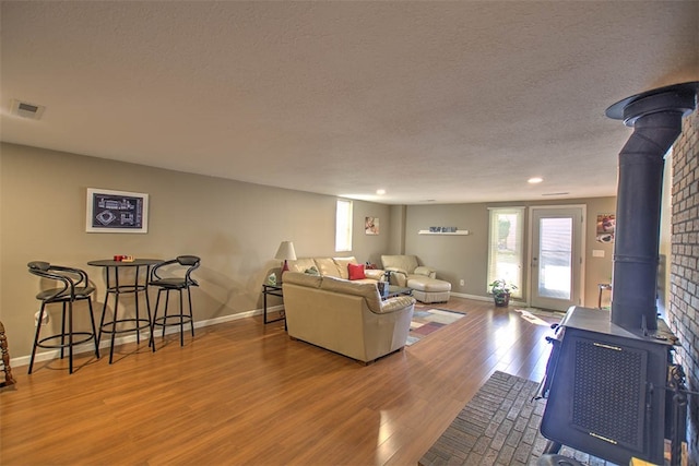 living room with a textured ceiling, hardwood / wood-style flooring, and a wood stove