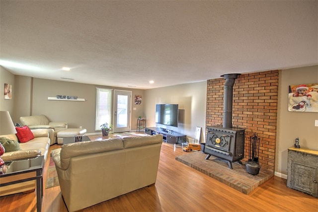 living room featuring a wood stove, light hardwood / wood-style floors, and a textured ceiling