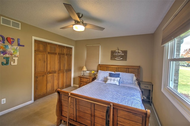 carpeted bedroom with ceiling fan, a closet, and a textured ceiling