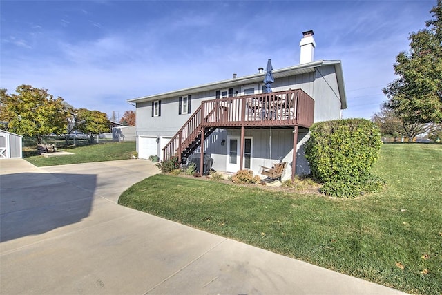 rear view of property with a garage, a yard, and a wooden deck