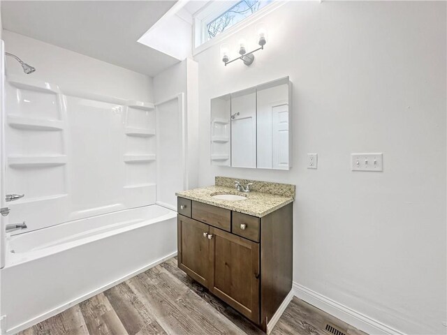 bathroom featuring baseboards, vanity, wood finished floors, and shower / bathtub combination