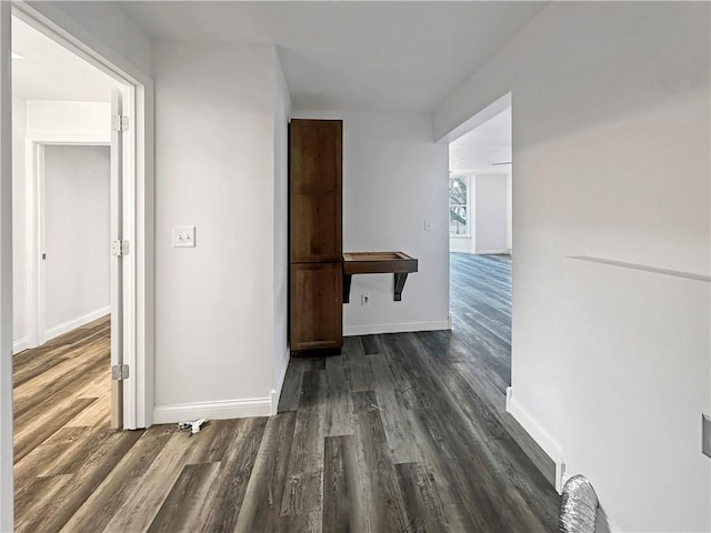 corridor with dark wood finished floors and baseboards