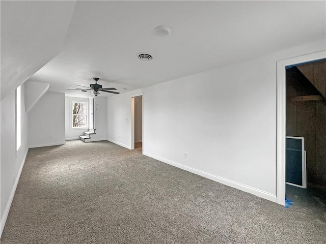 interior space featuring visible vents, lofted ceiling, a ceiling fan, carpet flooring, and baseboards