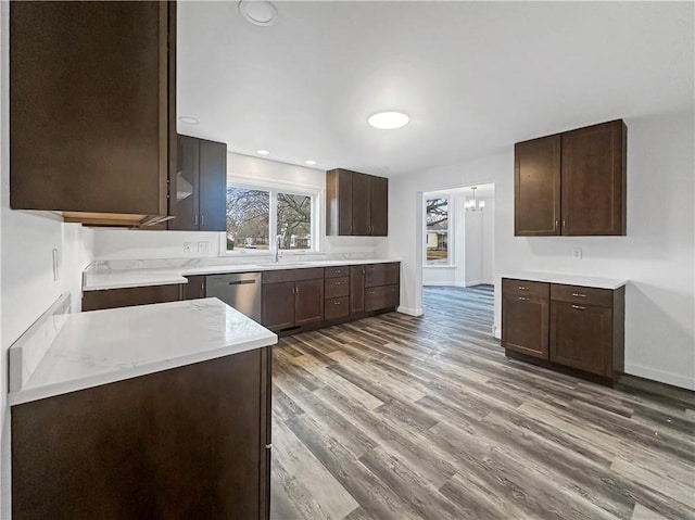 kitchen featuring wood finished floors, baseboards, light countertops, dark brown cabinets, and stainless steel dishwasher