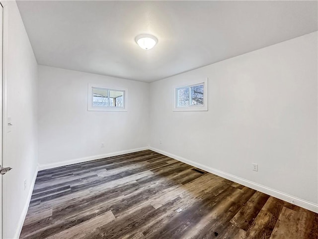 unfurnished room featuring visible vents, baseboards, a healthy amount of sunlight, and dark wood finished floors