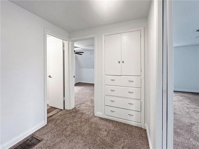 hallway featuring carpet, visible vents, and baseboards