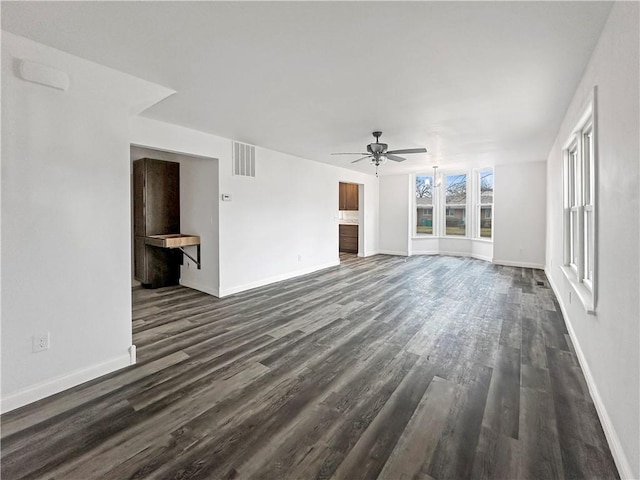 unfurnished living room featuring visible vents, baseboards, dark wood-type flooring, and a ceiling fan