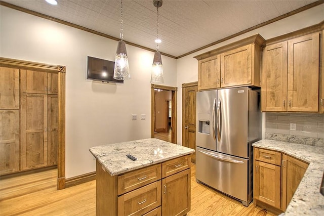 kitchen with crown molding, hanging light fixtures, light stone countertops, light wood-type flooring, and stainless steel fridge
