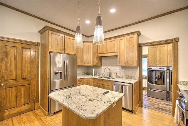 kitchen with stainless steel appliances, ornamental molding, a sink, and light wood finished floors