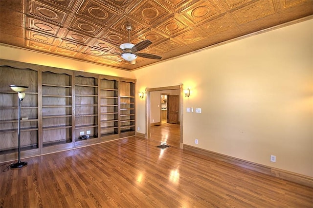 spare room featuring an ornate ceiling, ceiling fan, baseboards, and wood finished floors