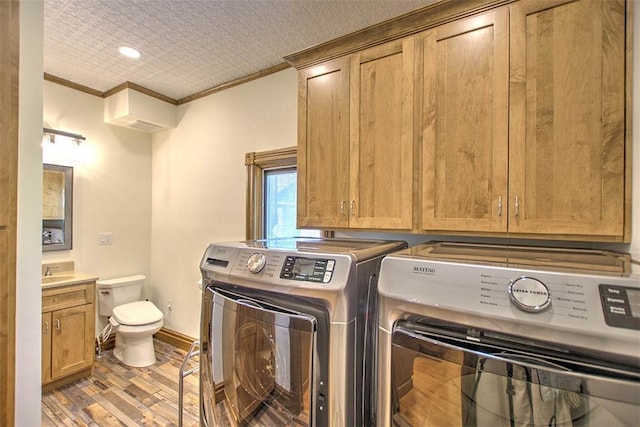 washroom with independent washer and dryer, crown molding, laundry area, a sink, and wood finished floors