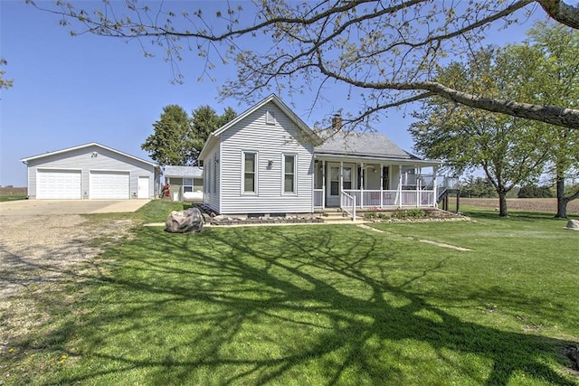 view of front facade with a porch, a garage, a front lawn, and an outbuilding