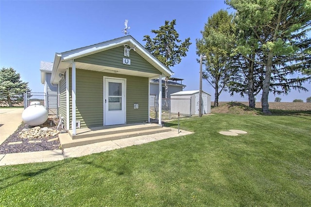 view of front of house featuring fence, a storage unit, an outbuilding, and a front lawn