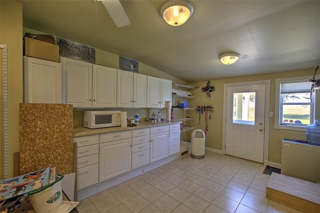 kitchen with light countertops, white cabinetry, white microwave, and vaulted ceiling