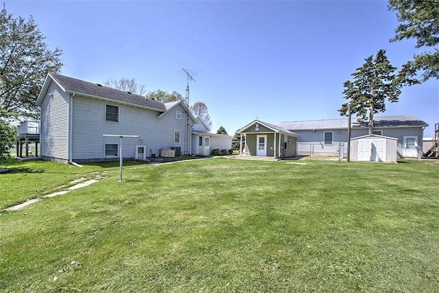 rear view of property featuring an outdoor structure, a lawn, a storage unit, and cooling unit
