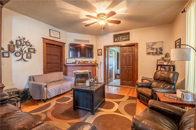 101 W N Water St, Bethany, IL 61914 - living room with a textured ceiling, wood finished floors, a brick fireplace, and a ceiling fan