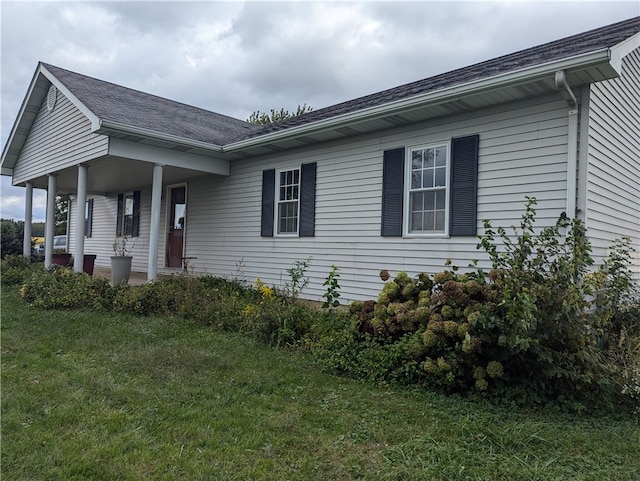 view of side of property with covered porch and a lawn