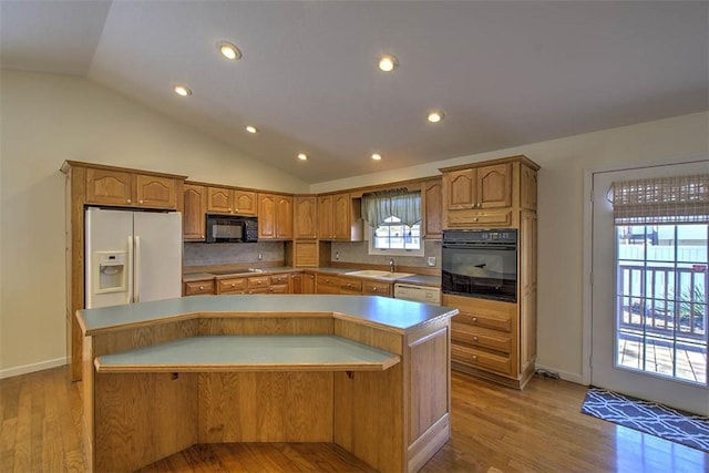 kitchen featuring lofted ceiling, a sink, a center island, black appliances, and light wood finished floors