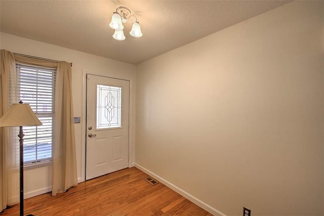 foyer with light wood-type flooring, baseboards, and visible vents