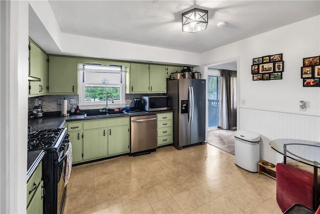 1450 W Westside Dr, Mt Zion, IL 62549 - kitchen featuring appliances with stainless steel finishes, a sink, green cabinetry, dark countertops, and a wainscoted wall