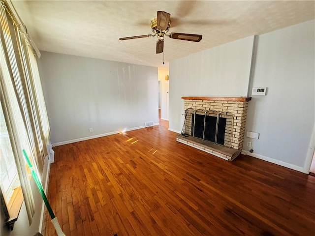 unfurnished living room featuring ceiling fan, a fireplace, baseboards, and wood finished floors