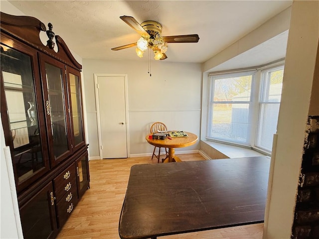 dining space featuring light wood-style floors, ceiling fan, and baseboards