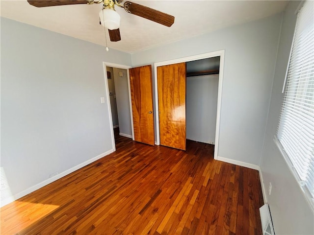 unfurnished bedroom featuring dark wood-style floors, a ceiling fan, baseboards, and a closet