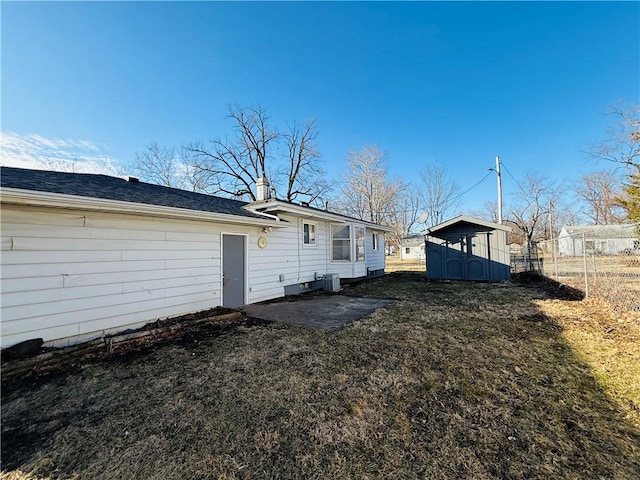 back of house featuring an outbuilding, a patio, central AC unit, a storage shed, and fence