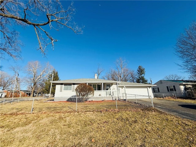 view of front of home with driveway, a front lawn, a fenced front yard, and an attached garage