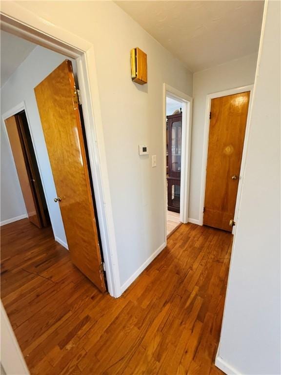 hall with baseboards and wood finished floors