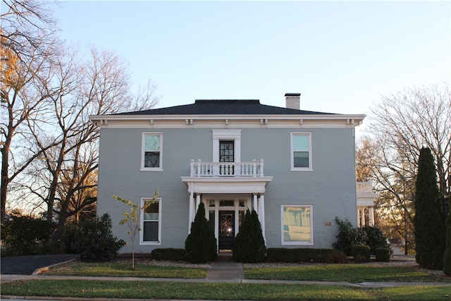 italianate-style house featuring a front yard and a balcony