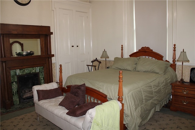 bedroom featuring carpet floors, a closet, and a tiled fireplace