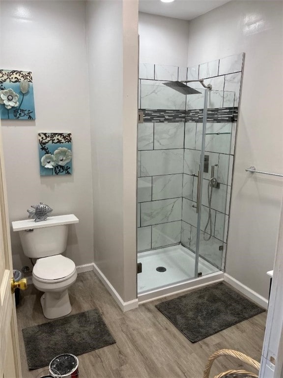 bathroom with hardwood / wood-style floors, a shower with shower door, and toilet