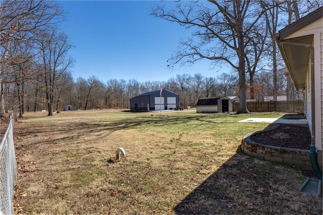 view of yard with an outbuilding, a storage unit, a garage, and fence