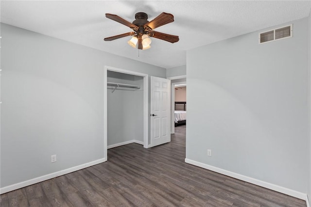 unfurnished bedroom with baseboards, visible vents, wood finished floors, and a closet