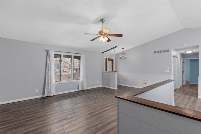spare room featuring wood finished floors, vaulted ceiling, ceiling fan with notable chandelier, baseboards, and visible vents
