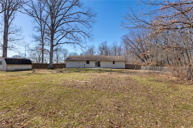 rear view of property with a fenced backyard, an outbuilding, and a yard