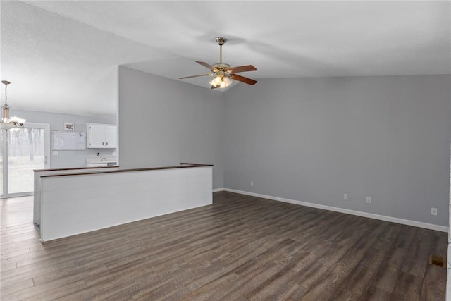 unfurnished living room featuring dark wood-style flooring, baseboards, vaulted ceiling, and ceiling fan with notable chandelier