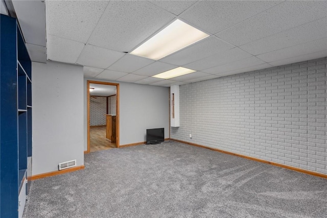 finished below grade area with a paneled ceiling, visible vents, carpet floors, and baseboards