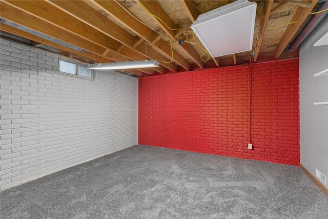 basement featuring carpet and brick wall