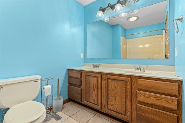 bathroom featuring tile patterned floors, toilet, double vanity, and a sink