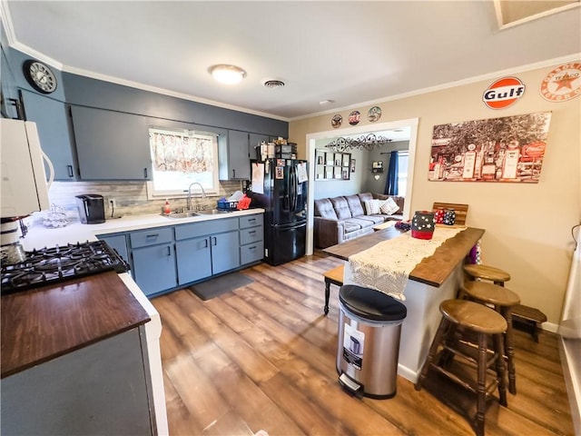 421 S 8th St, Marshall, IL 62441 - kitchen with black fridge, light wood-style floors, ornamental molding, backsplash, and a kitchen breakfast bar
