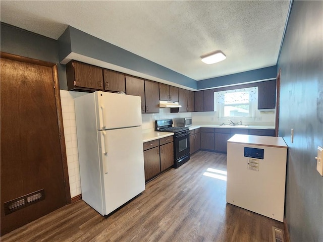 324 Madison St, Mason, IL 62443 - kitchen featuring black gas stove, freestanding refrigerator, a textured ceiling, wood finished floors, and light countertops