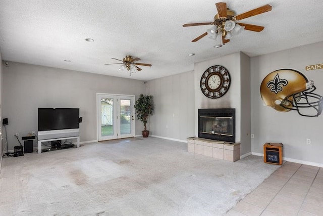 unfurnished living room with a tiled fireplace, ceiling fan, light carpet, and a textured ceiling