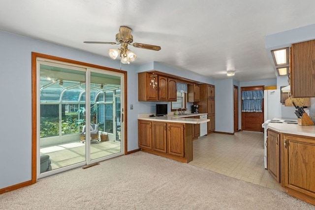 kitchen with kitchen peninsula, white appliances, light colored carpet, and ceiling fan